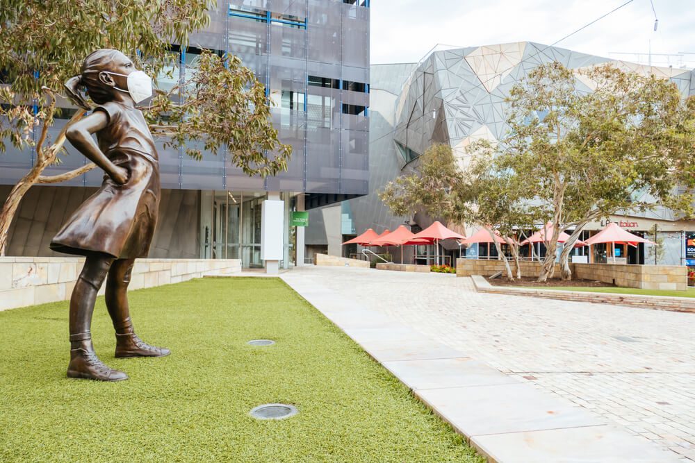 Australia Lockdown Federation Square and a masked statue of Fearless Girl in Melbourne is quiet and empty during the Coronavirus pandemic